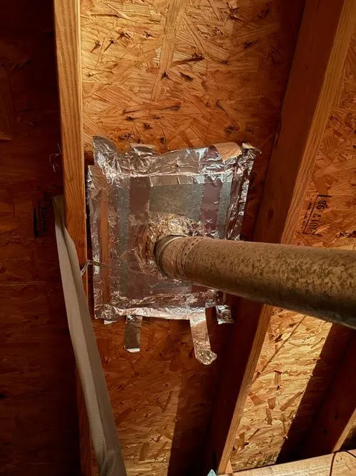 Exhaust vent pipe penetration sealed in an attic space