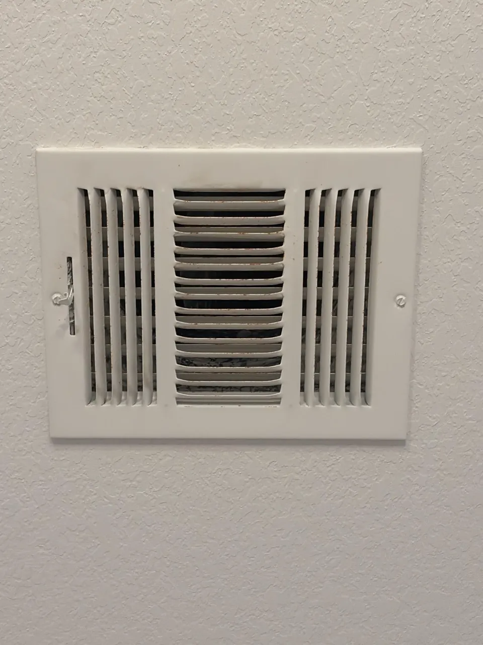 Interior HVAC supply register on a textured wall