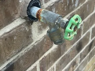 Exterior hose bib and plumbing fixture on a brick wall