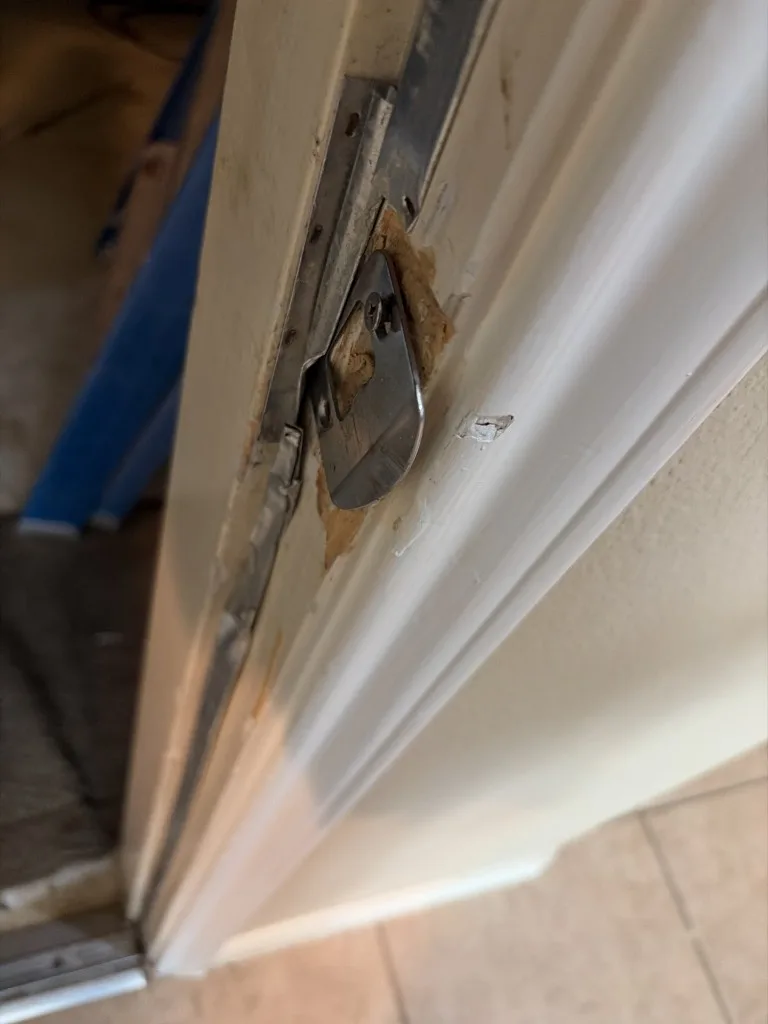 Damaged door jamb and strike plate from forced entry or impact