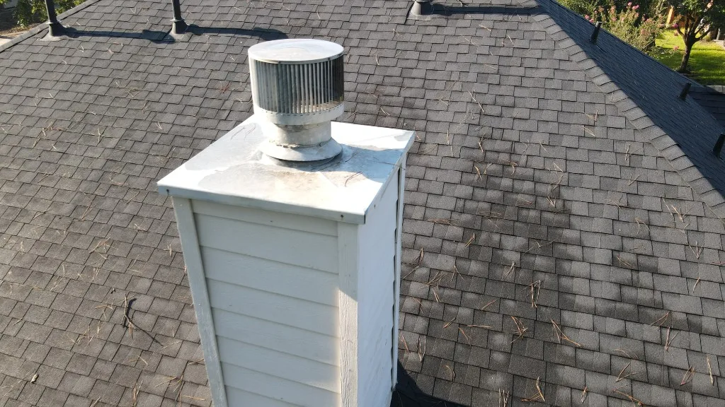 Chimney and roof vent on an asphalt shingle roof