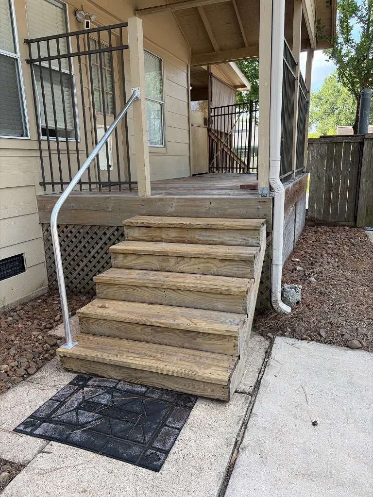 Exterior wooden porch stairs, railing, and deck structure