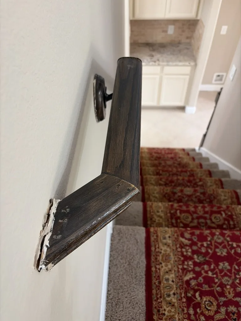 Handrail pulled away from the wall at the top of a stairway